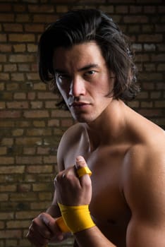 Bare chested young Malaysian boxer wrapping straps around hands