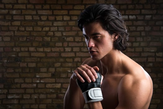 Bare chested young Malaysian boxer wearing fingerless boxing gloves