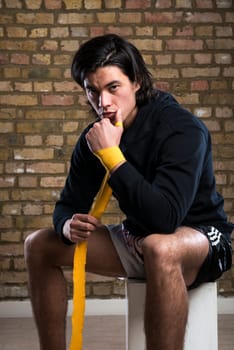 Young Malaysian boxer  wearing hoodie and wrapping straps around hands