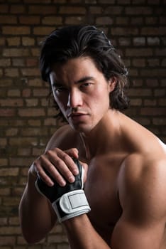 Bare chested young Malaysian boxer wearing fingerless boxing gloves