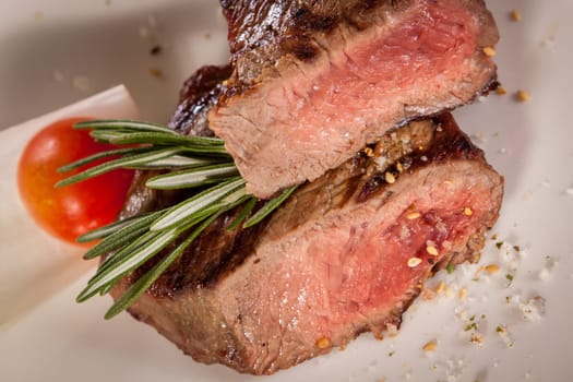 Medium fried beef steak fillet with pepper and rosemary sliced on a plate