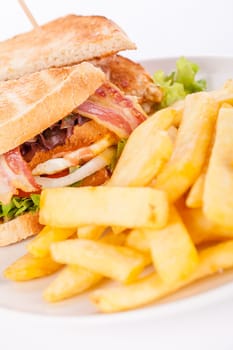 Club sandwich on toasted white bread with bacon and fries fried fries on a plate isolated against a white background