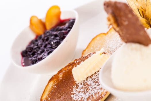 Delicious sweet pancakes as desser with vanilla ice cream prepared on a white plate insulated against a white background