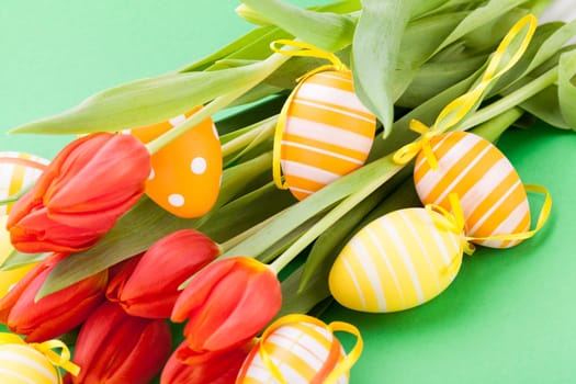 Colourful yellow and red Tulip with Easter eggs decorated at Easter with text space on green background