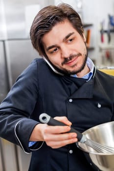 young chef on the phone while cooking in the restaurant kitchen work success stress communication