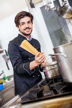 young chef prepares fresh Italian pasta spaghetti at the herd in the restaurant kitchen too