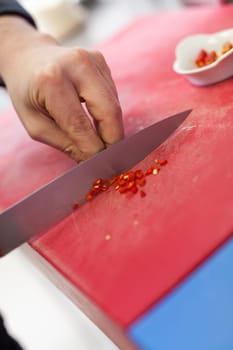 chef cuts fresh red chilli small in the restaurant kitchen to eat gatsronomie food