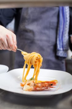 chef prepares fresh pasta spaghetti with shrimp crusts on a plate at the restaurant