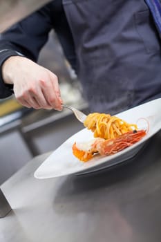 chef prepares fresh pasta spaghetti with shrimp crusts on a plate at the restaurant