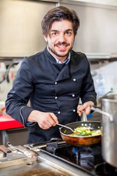young adult chef in the restaurant kitchen while cooking at the herd preparation