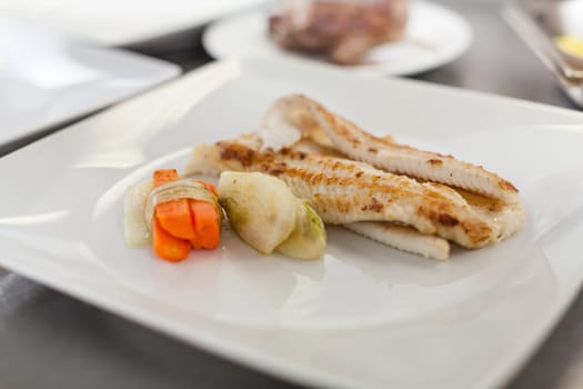 fresh fried fish fillet with vegetables and sauce on a teller restaurant kitchen preparation dinner