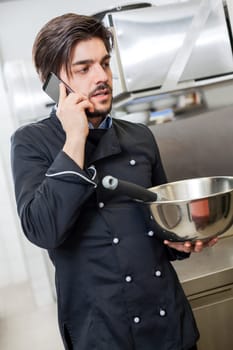 young chef on the phone while cooking in the restaurant kitchen work success stress communication