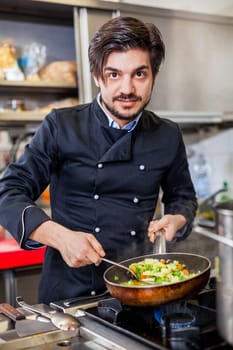 young adult chef in the restaurant kitchen while cooking at the herd preparation