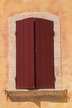Close-up view of old window with red wooden shutters. Mediterranean architecture. Provence, France.