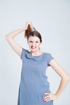 Studio portrait of attractive and stylish woman playfully pulling her hair while grimacing