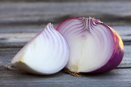 Close up view of two halved fresh red onions on a old wooden Table