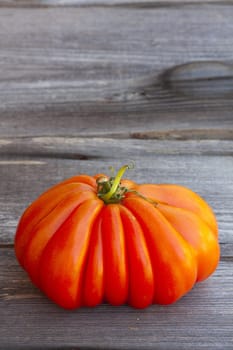 One large Beefsteak Tomatoe fresh from the Weekly Market on a old wooden Table