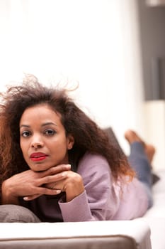 beautiful afro american woman staring at camera lying on a sofa