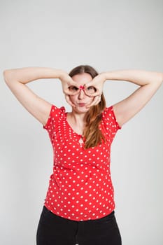 Studio portrait of attractive woman with pursed lips looking through finger goggles