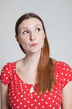 Studio portrait of thoughtful looking attractive woman with pursed lips looking to side