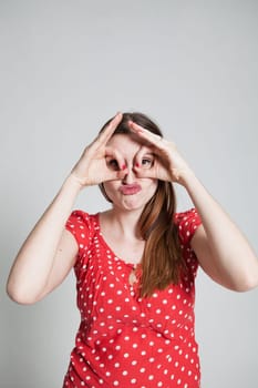 Studio portrait of attractive woman with pursed lips looking through finger goggles