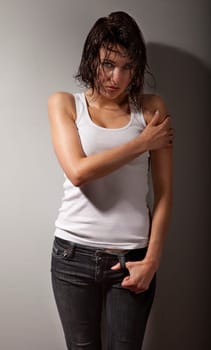 Studio photo of pretty, young, distraught woman stand against wall.