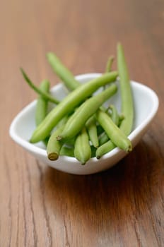 Green beans in a white bowl on a wooden table
