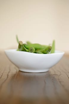 Green beans in a white bowl on a wooden table