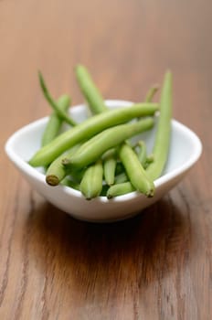 Green beans in a white bowl on a wooden table