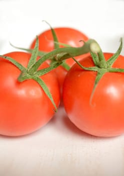 Three tomatoes on a white wooden bowl, close up with selective focus on foreground
