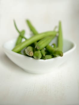 Green beans in a white bowl on a wooden table