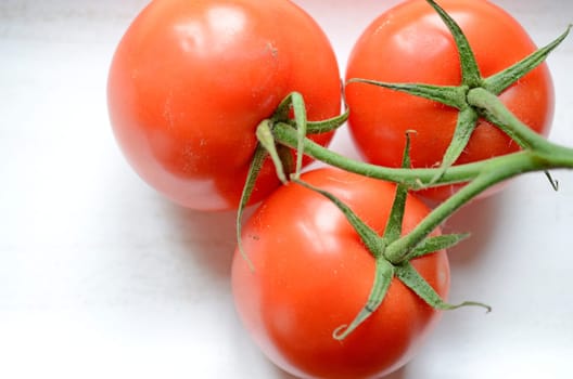 Three tomatoes on a white wooden bowl