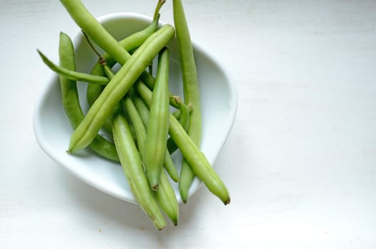 Green beans in a white bowl on a wooden table