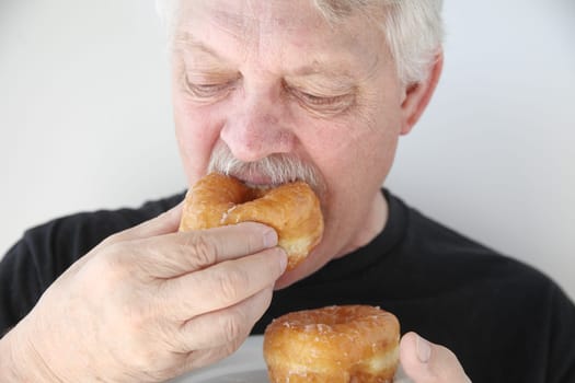 older man enjoys a bakery yeast doughnut
