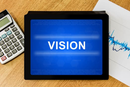 vision word on digital tablet with calculator and financial graph