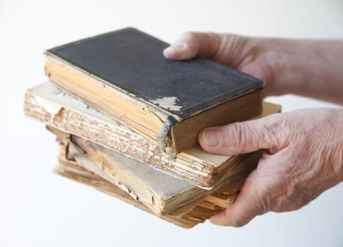 a man holds several old, damaged books