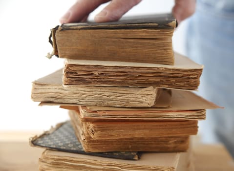 a man's hand on a stack of old books