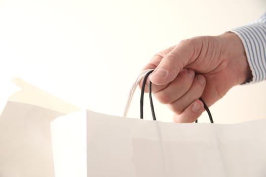 a man's hand with two store paper bags