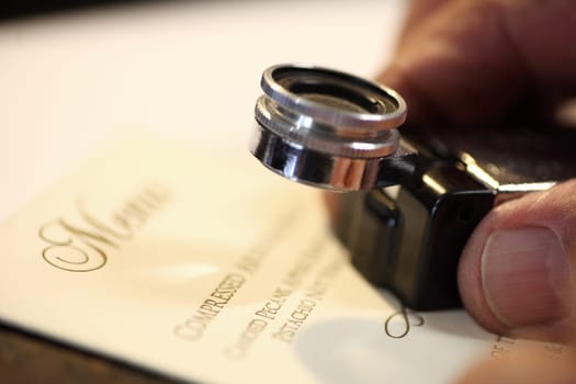 man uses a magnifier to look closely at his work