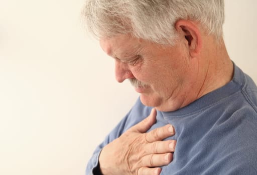 an older man with his hands to his chest, head lowered