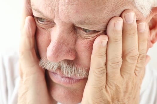 older man holds both hands up to his face