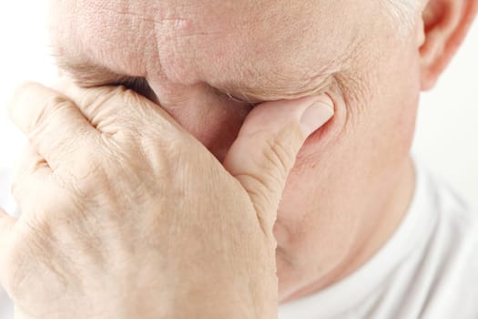 overworked older man tries to relieve his eyestrain