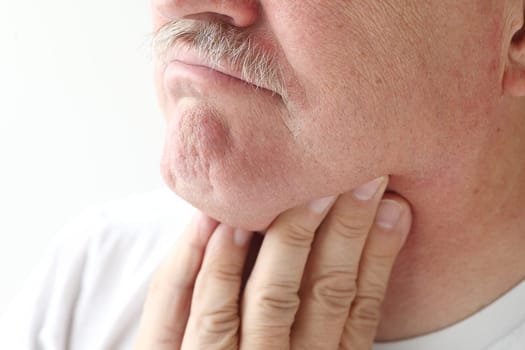 man holds his fingers up to his aching throat