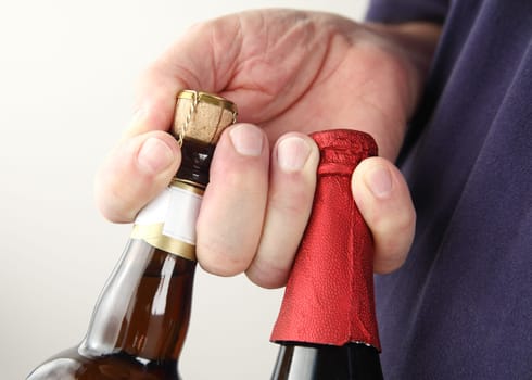two large beer bottles in man's fingers