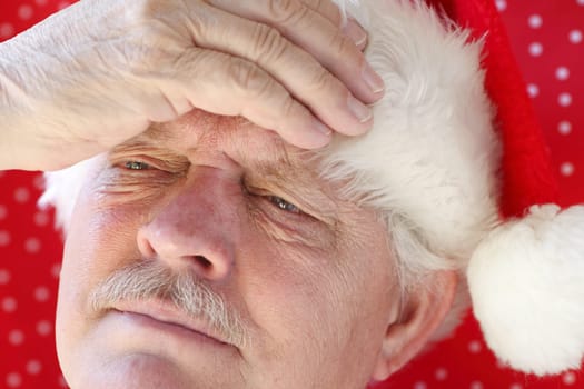 senior man in Santa hat with a headache