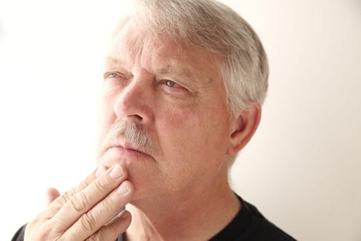 older man with fingers on chin and pensive expression