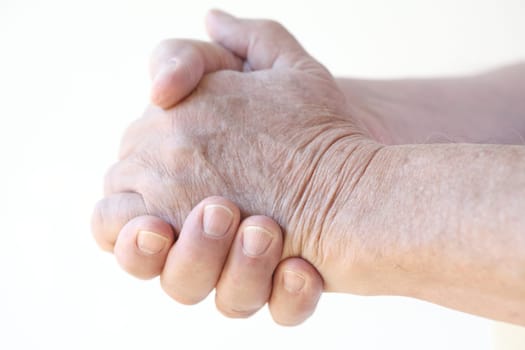 senior man clasps his hands together