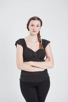 Studio portrait of thoughtful looking attractive woman with pigtail and arms folded