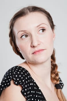 Closeup studio portrait of thoughtful looking attractive woman with pigtail looking to side