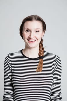 Studio portrait of happy smiling attractive woman with pigtail wearing striped blouse